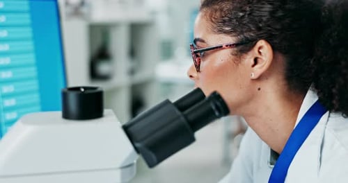 Woman Scientist Looking Into Microscope in Laboratory