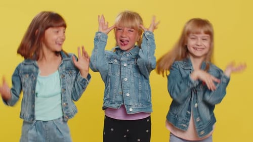 Happy Girls Dancing Together on Yellow Background