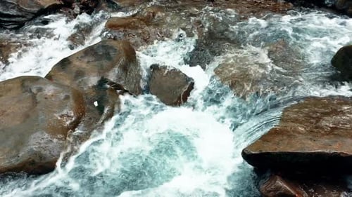 Kristallklarer schäumender Wasserstrom, der durch Steine im Bergwald fließt