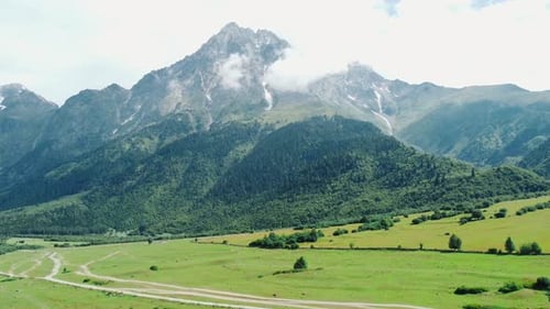 Clouds embracing majestic mountain peak over lush green valley