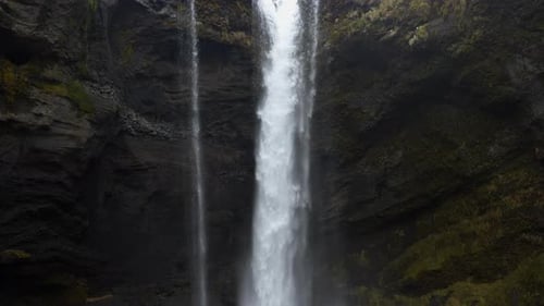 Majestic Waterfall Flows Between Mossy Rock Formations