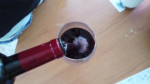 Rotwein auf eine Tasse gießen