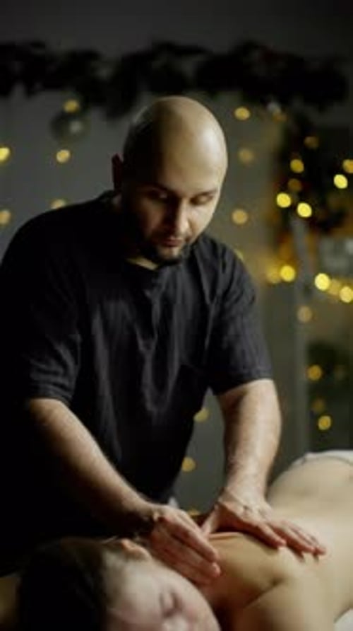 Man Massaging Woman's Back in Dark Room