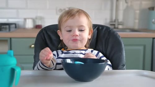Happy Infant Eating Food in High Chair at Home