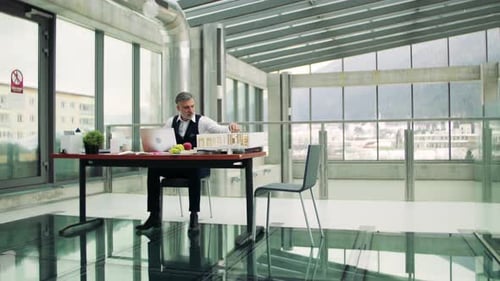 Mature Architect with Laptop and Model of a House in Office, Working