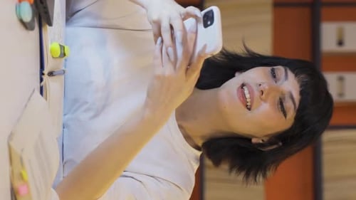 Woman Smiling and Using Phone at Desk