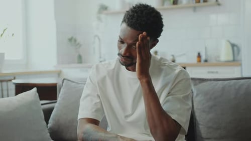 Man Sitting on Couch with Headache