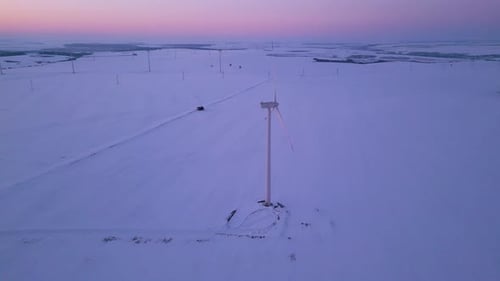 Aerial View of a Wind Farm in a Snowy Landscape at Sunset Large Wind Turbines Stand Tall Against the