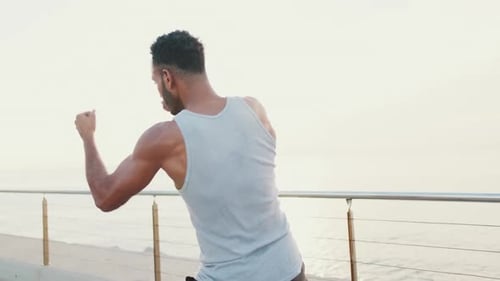 Young fit athlete boxer practicing punching technique while standing on the embankment