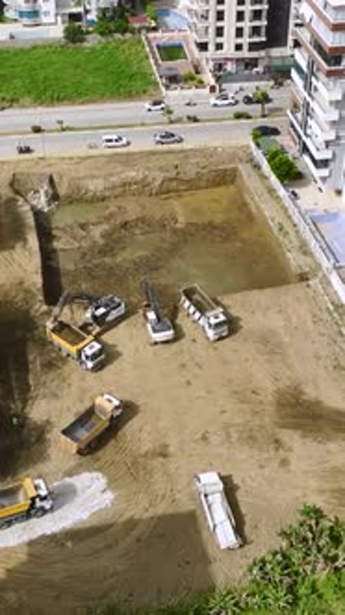 Vertical Video Heavy Machinery and Workers Digging and Pouring Foundations on a Construction Site