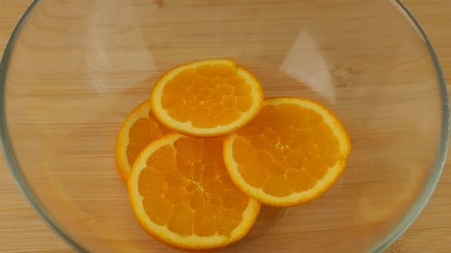 Orange Slices Falling Into a Glass Bowl