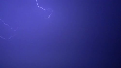 Flashes of lightning in the night sky among thunderclouds.