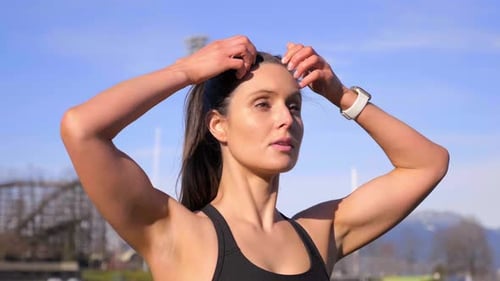 Attractive athletic woman tying up hair before run Medium shot