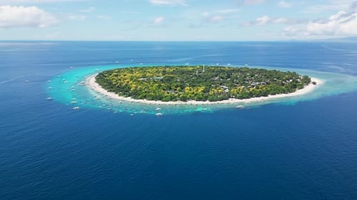 Aerial View of Almost Perfectly Round Green Tropical Island Next to Which Tourist Boats and Yachts