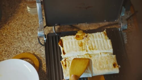 Top View of an Open Grill Removing the Finished Shawarma with Wooden Spatulas