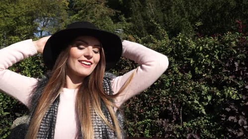 Smiling Young Woman in Hat Poses in Park
