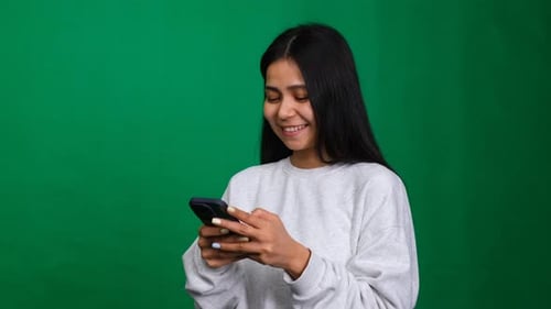 Smiling Young Adult Looking at Phone in Studio