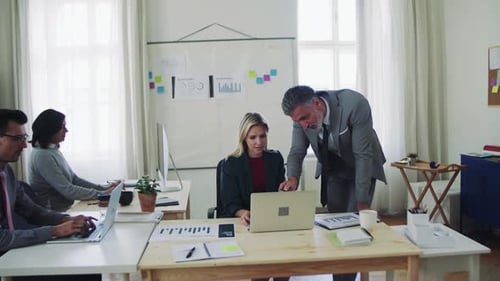 Diverse business team collaborating on laptop in modern office space