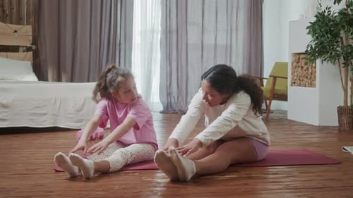 Girl and Woman Stretching Together on Yoga Mat