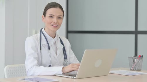 Female Doctor Working on Laptop, Smiling