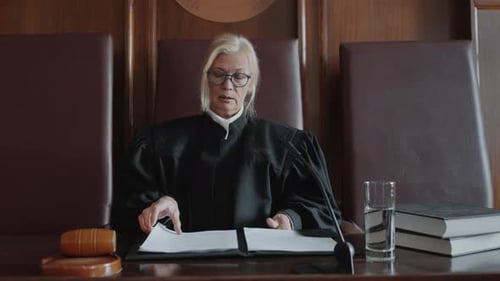 Female Judge Reads Documents in Courtroom Setting