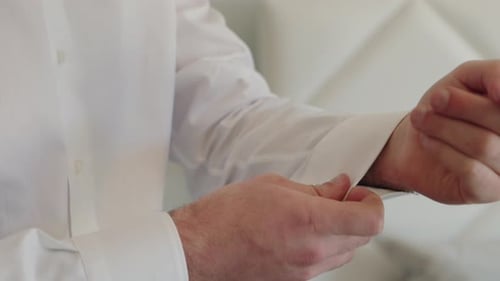 close up of man fastening white shirt cuff before formal event
