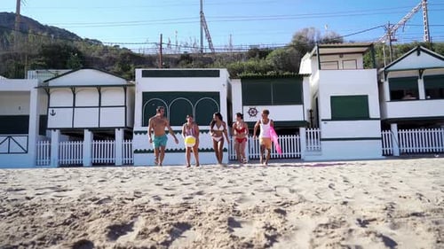 Happy Group of Friends on the Beach Running Towards the Camera to Go to the Sea to Enjoy Summer