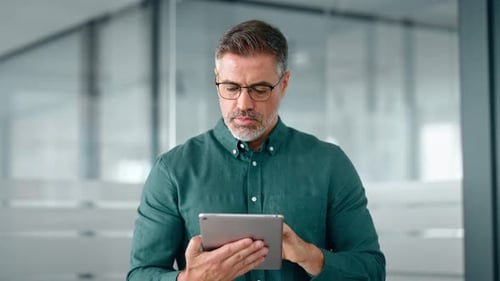 Smiling Busy Middle Aged Business Man Investor Using Tablet Standing in Office