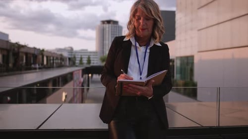 Business Woman Writing in Notebook Outdoors on Terrace
