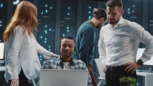 Team Discussing Work with Colleague at Laptop in Office