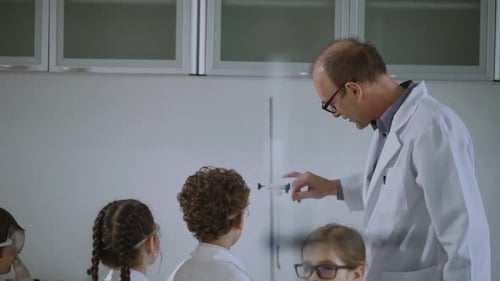 Teacher Explaining Science Experiment to Children in Lab