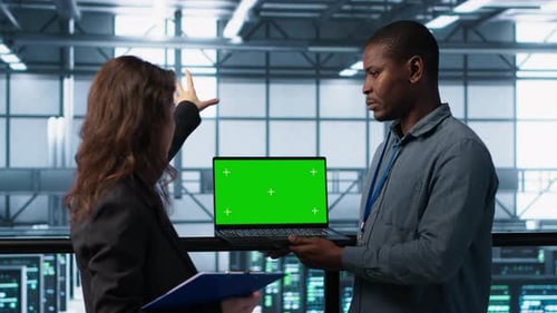 Techniker im Rechenzentrum überprüfen mithilfe eines Greenscreen-Laptops den Zustand der Geräte
