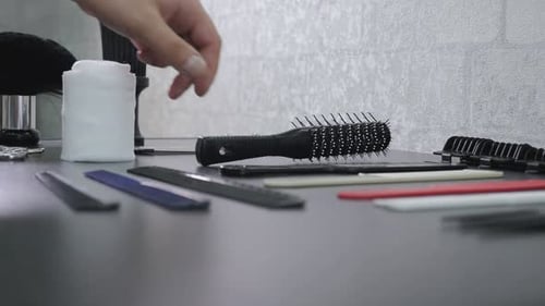 Barber Picks Up Hairbrush from Stylist Table