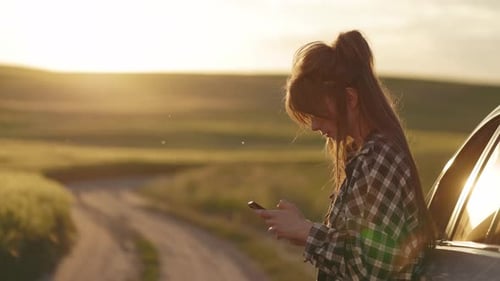 Woman Using Phone By Car On Rural Road