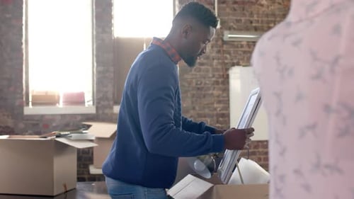 Diverse colleagues packing boxes with documents and office items in creative office in slow motion