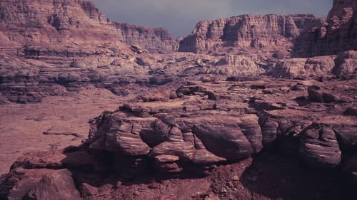 Vast Desert Landscape with Rugged Rock Formations Under Cloudy Sky