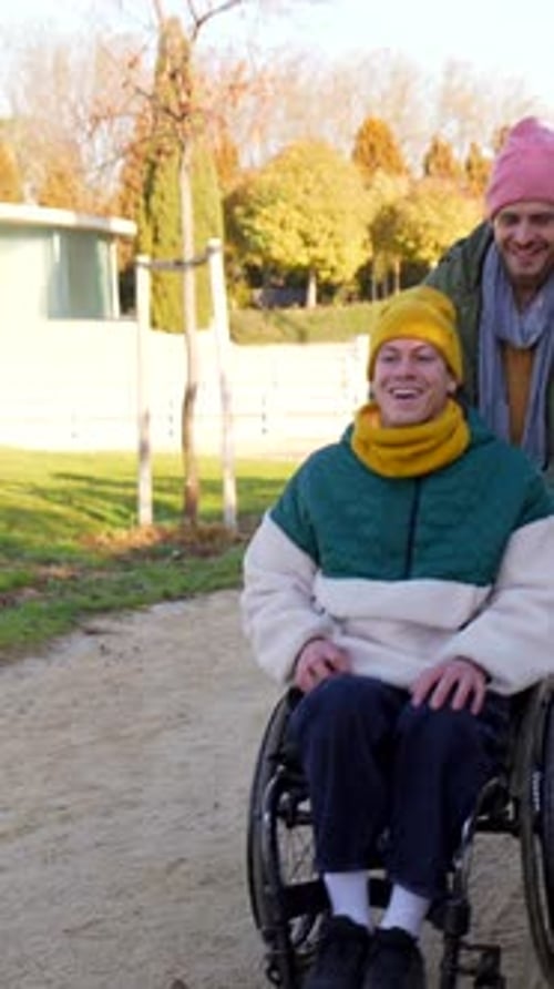 Man Pushing Friend in Wheelchair in Park