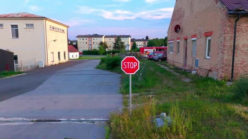 A Quiet Suburban Street Features a Stop Sign, Grassy Patches, and a Mix of Old Brick and Modern Buil