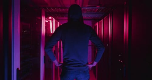 Hooded Person Standing in Server Room at Night