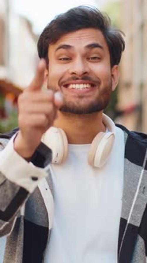 Junger Inder, der aufgeregt lächelt und auf Sie zeigt, wie er den glücklichen Gewinner in der City Street auswählt