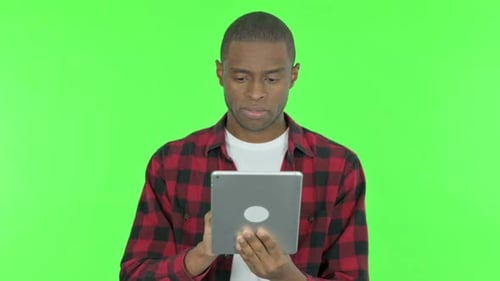 African Man using Digital Tablet on Green Background