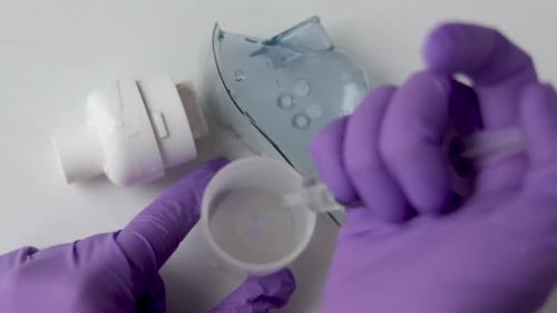 doctor hands in surgical gloves preparing solution for inhaler medication for respiratory infection