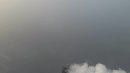 Aerial view of smoking factory chimneys towering above dense fog, Netherlands