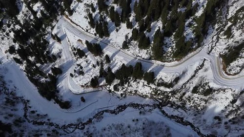 Winding Snowy Road Through a Winter Forest in the Mountains