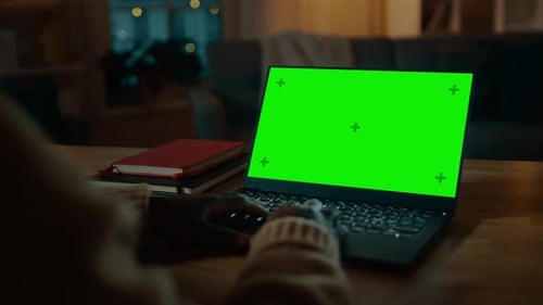 Beautiful Black Woman Sitting at Her Desk Works on a Laptop with Green Chroma Key Screen. Late at N