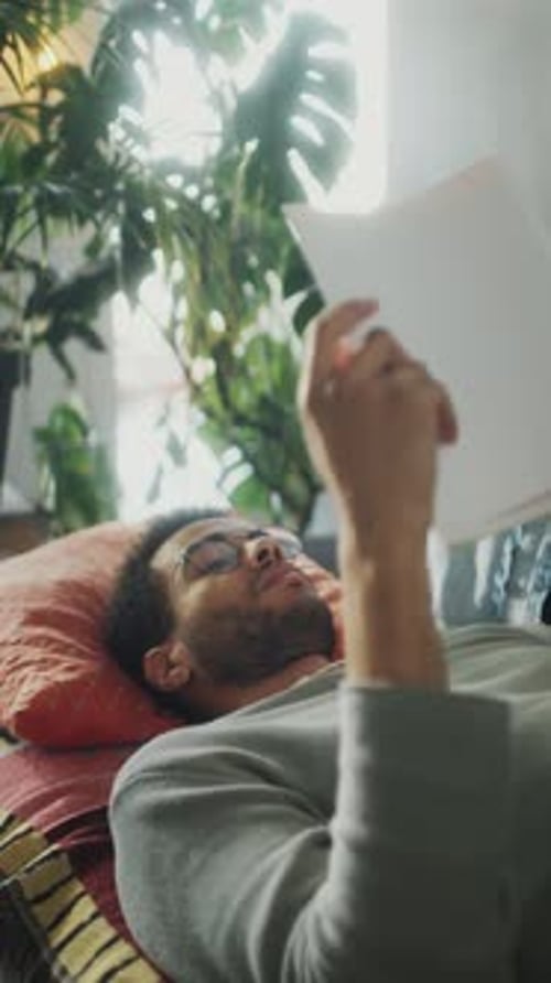 Man Reading Document Lying on a Couch