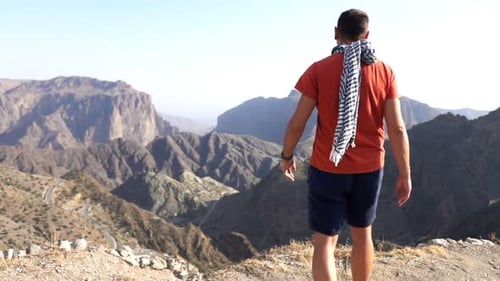 Young man in scarf admiring beautiful canyon view in mountains super slow motion