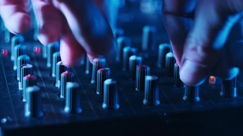 Sound Engineer Move Faders Level on Audio Mixer Console in Neon Light CloseUp