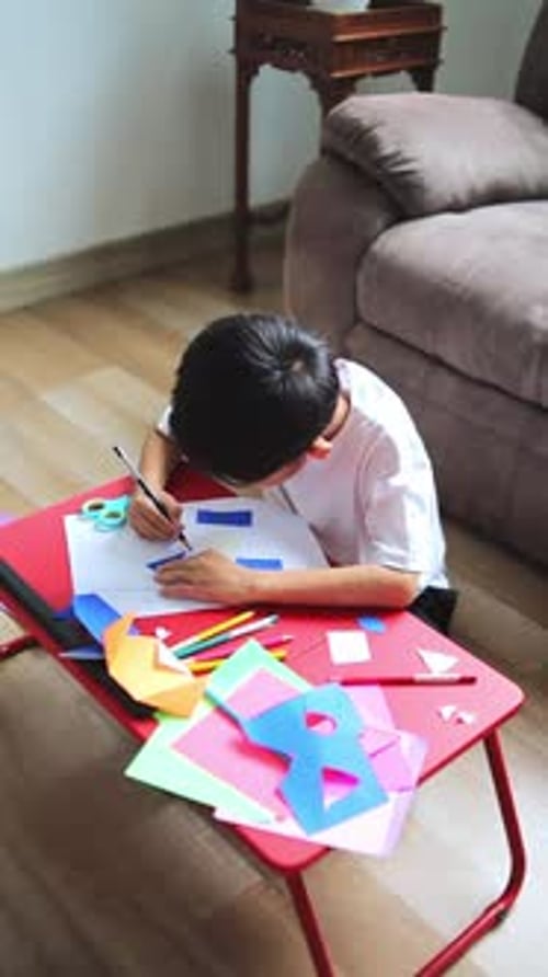 Jeune garçon asiatique apprenant et développant la motricité fine au bureau coloré