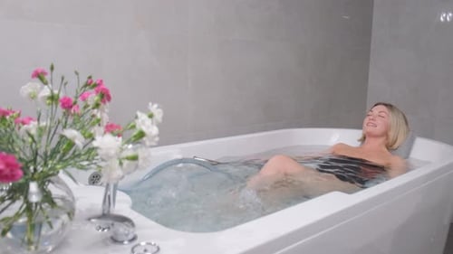 Beautiful Woman Relaxes in Bath Hydromassage Therapy in SPA